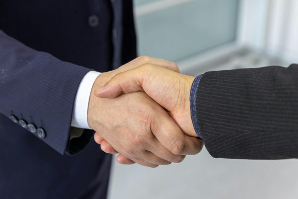 Close-up of two business professionals shaking hands, symbolizing partnership and collaboration.
